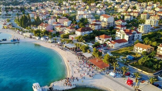 An aerial view of a coastal town with a beach, residential buildings, and boats. - Apartments Antonia (Okrug)