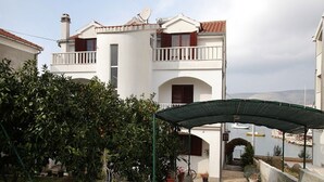 A two-story building with a balcony, a covered entrance, and a view of the sea. - Apartments Antonia (Okrug)