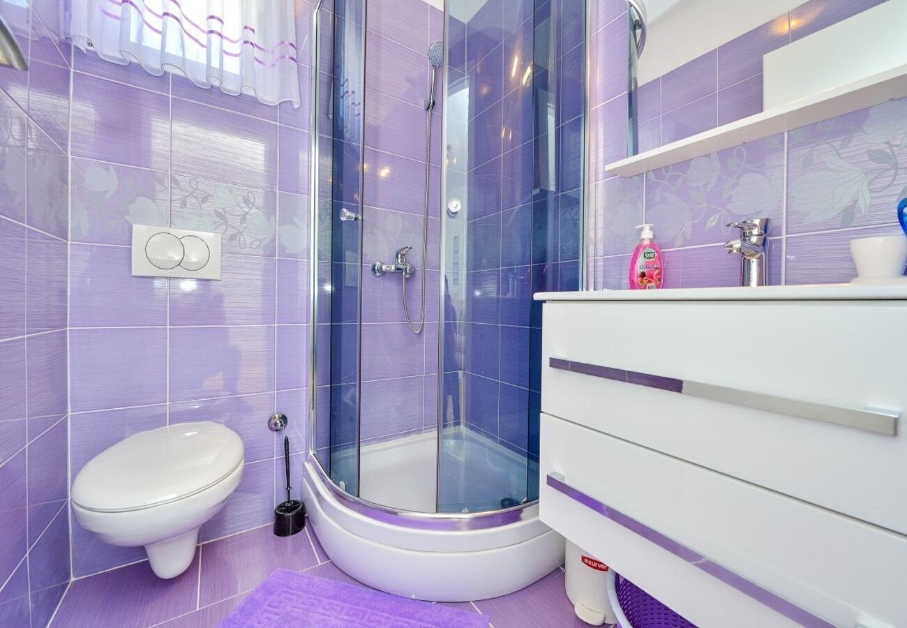 A bathroom with a glass shower enclosure, a white toilet, and a white vanity with a mirror.