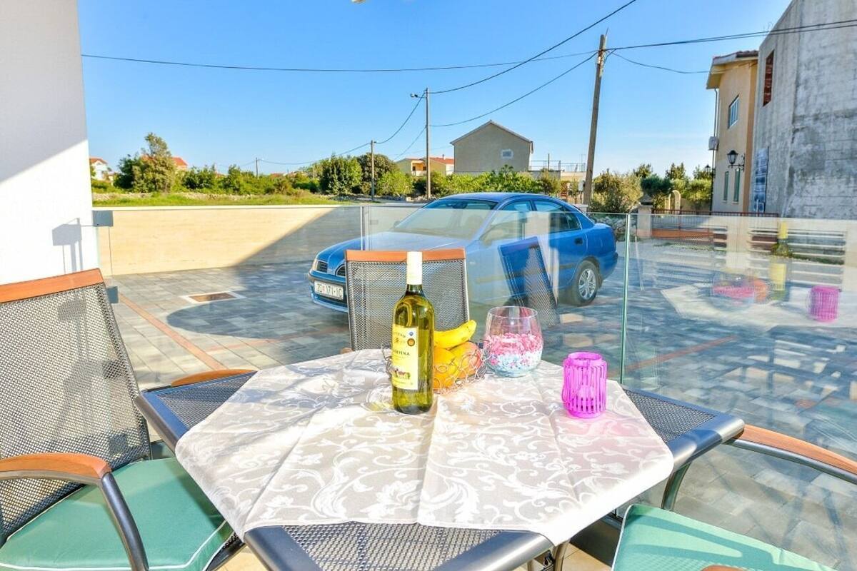 An outdoor seating area with a table, chairs, and a bottle of wine.