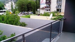A balcony with a glass railing overlooking a parking area and buildings. - House Marus (Omis)