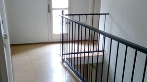 A spacious room with a tiled floor, a black metal railing, and a door leading to another room. - House Marus (Omis)