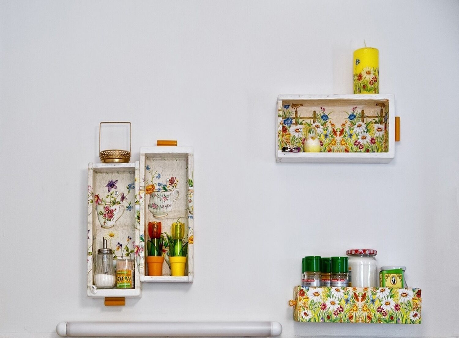 A kitchen with a white cabinet containing a glass jar, a metal container, and colorful potted plants.