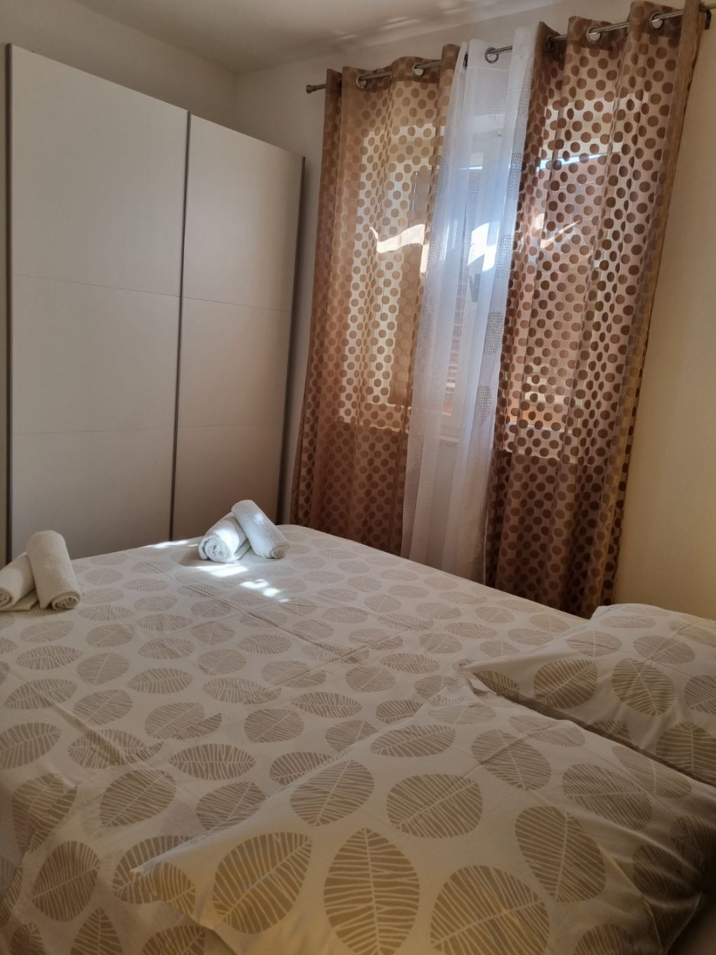 Une chambre d’hôtel avec un lit, une armoire et des rideaux.