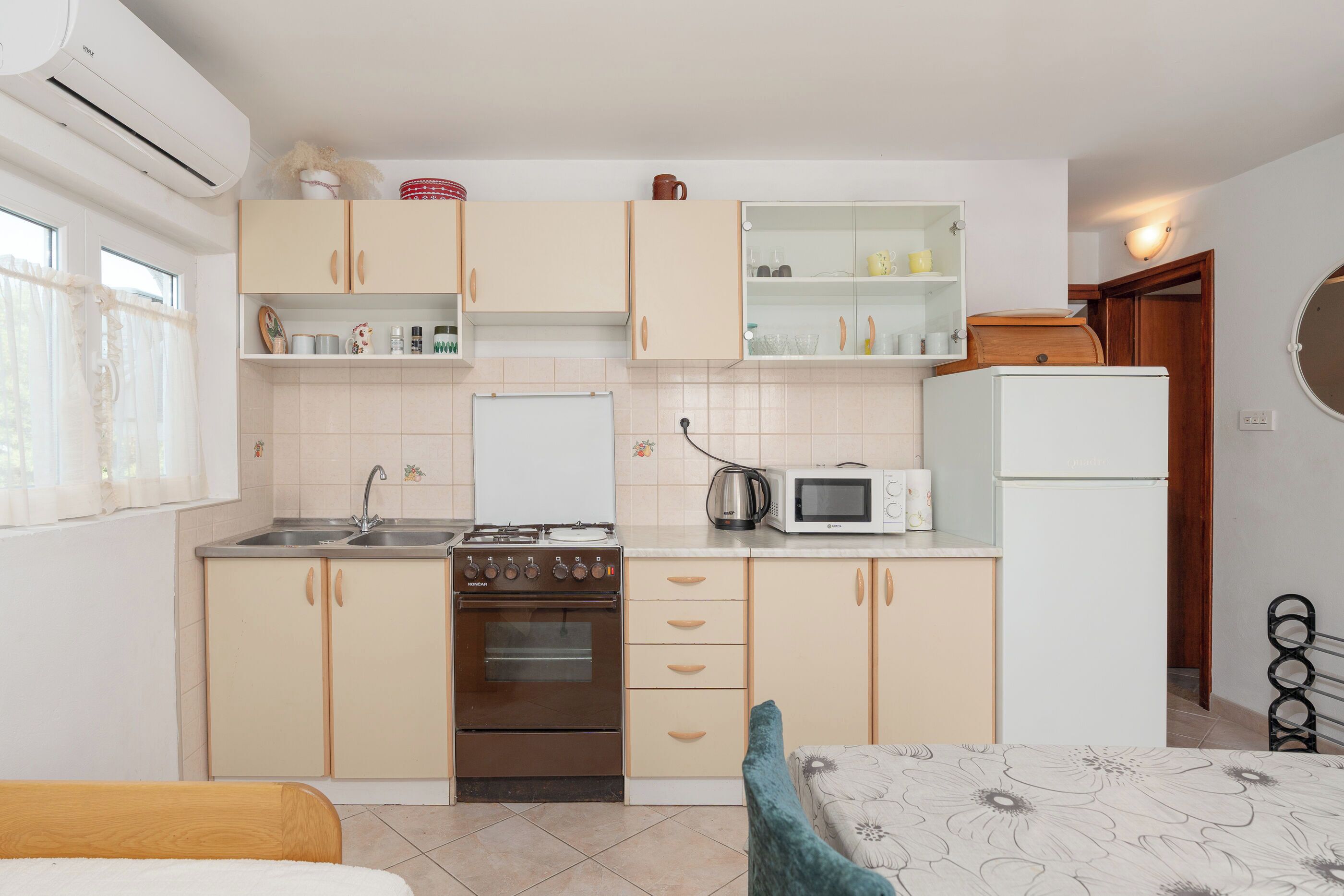 Eine kleine Küche mit Herd, Mikrowelle und Kühlschrank.