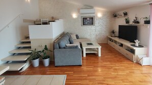 A modern living room with a staircase, grey sofa, flat-screen TV, and potted plants. - Apartment Damir (Tucepi)