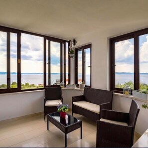 A balcony with wicker furniture, a glass table, and potted plants. - Apartment Damir (Tucepi)