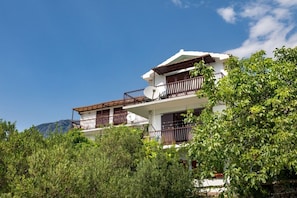 A multi-story building with balconies, surrounded by greenery and a clear sky. - Apartment Damir (Tucepi)