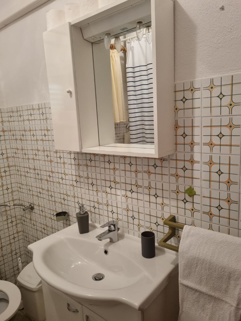 Un baño con un lavamanos blanco, un espejo encima y una cortina de ducha.