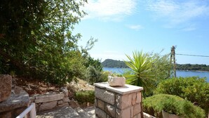 Un espace extérieur aménagé avec des sièges en pierre, offrant une vue sur la mer et les collines.