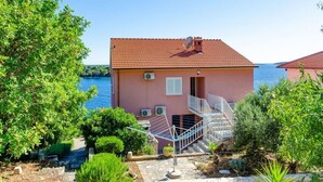Un bâtiment rose avec un toit recouvert de tuiles rouges, un escalier et une vue sur un lac.