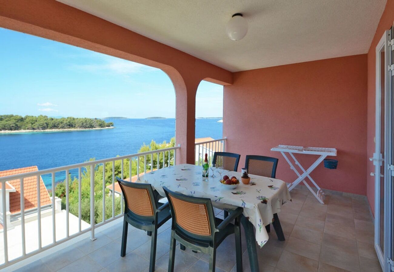 A balcony with a table and chairs, overlooking a body of water and greenery.