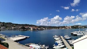 Un puerto deportivo con barcos amarrados, cielo despejado y un paisaje montañoso al fondo.