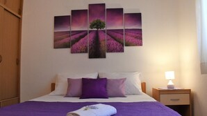 A hotel room with a large bed, a nightstand with a lamp, and a wall with a lavender field painting. - Apartments Frama (Bol)