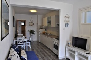 A compact living space with a kitchenette, a dining area, and a seating area with a sofa. - Apartments Frama (Bol)