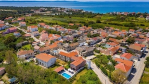 An aerial view of a coastal village with houses, a swimming pool, and a clear view of the sea. - House Luxury Villa With Pool (Nin)