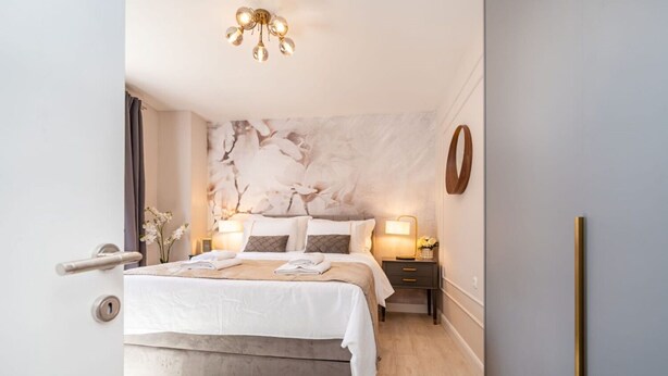 A modern bedroom with a large bed, bedside tables, a chandelier, and a marble wall. - House Luxury Villa With Pool (Nin)