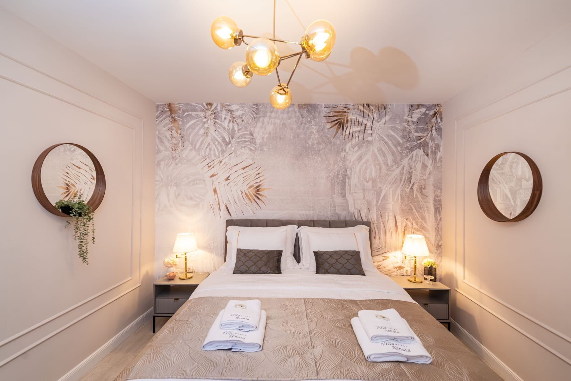 Hotelkamer met een groot bed, twee nachtkastjes met lampen, een spiegel aan de muur en een plafondlamp.