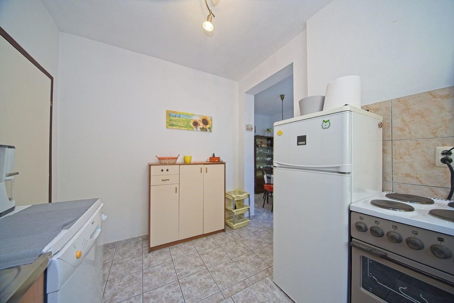 Eine kleine Küche mit Kühlschrank, Herd und einem Hängeschrank.