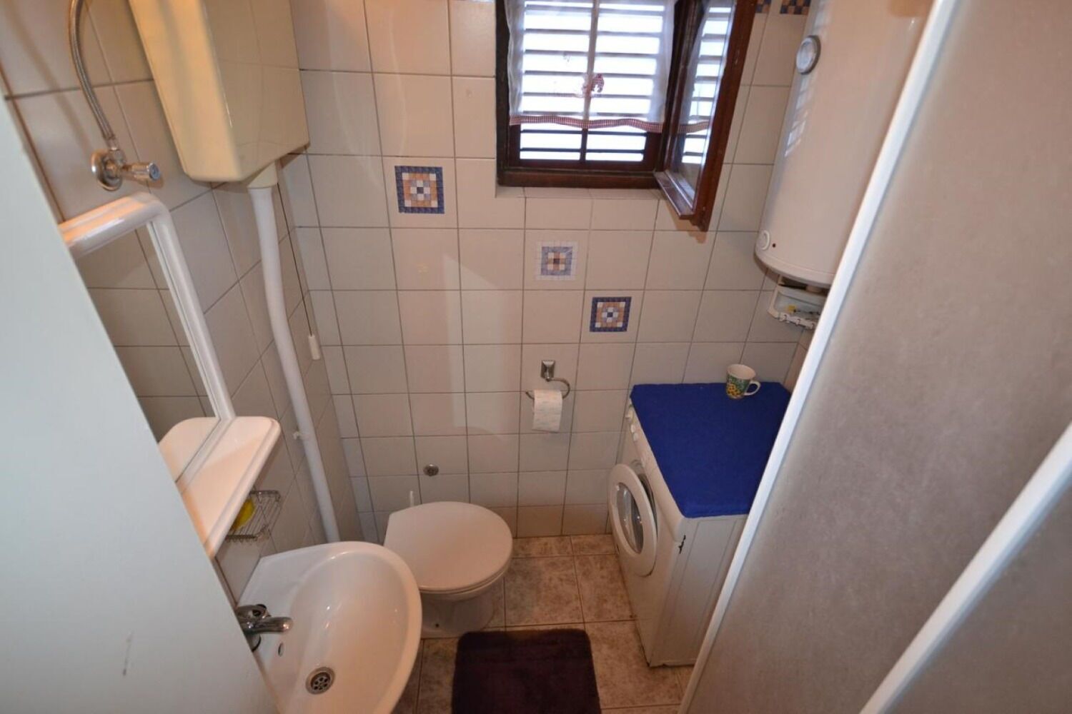 A compact bathroom with a toilet, sink, and washing machine.