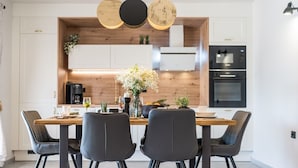 Una cucina moderna con una parete decorata in legno, un tavolo da pranzo con quattro sedie e luci a sospensione.