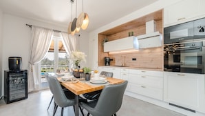 Una cucina moderna con mobili bianchi, un piano di lavoro in legno e un forno Bosch.