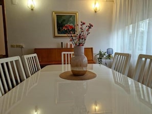 Ett matbord med en genomskinlig glasvas i mitten, omgivet av vita stolar.