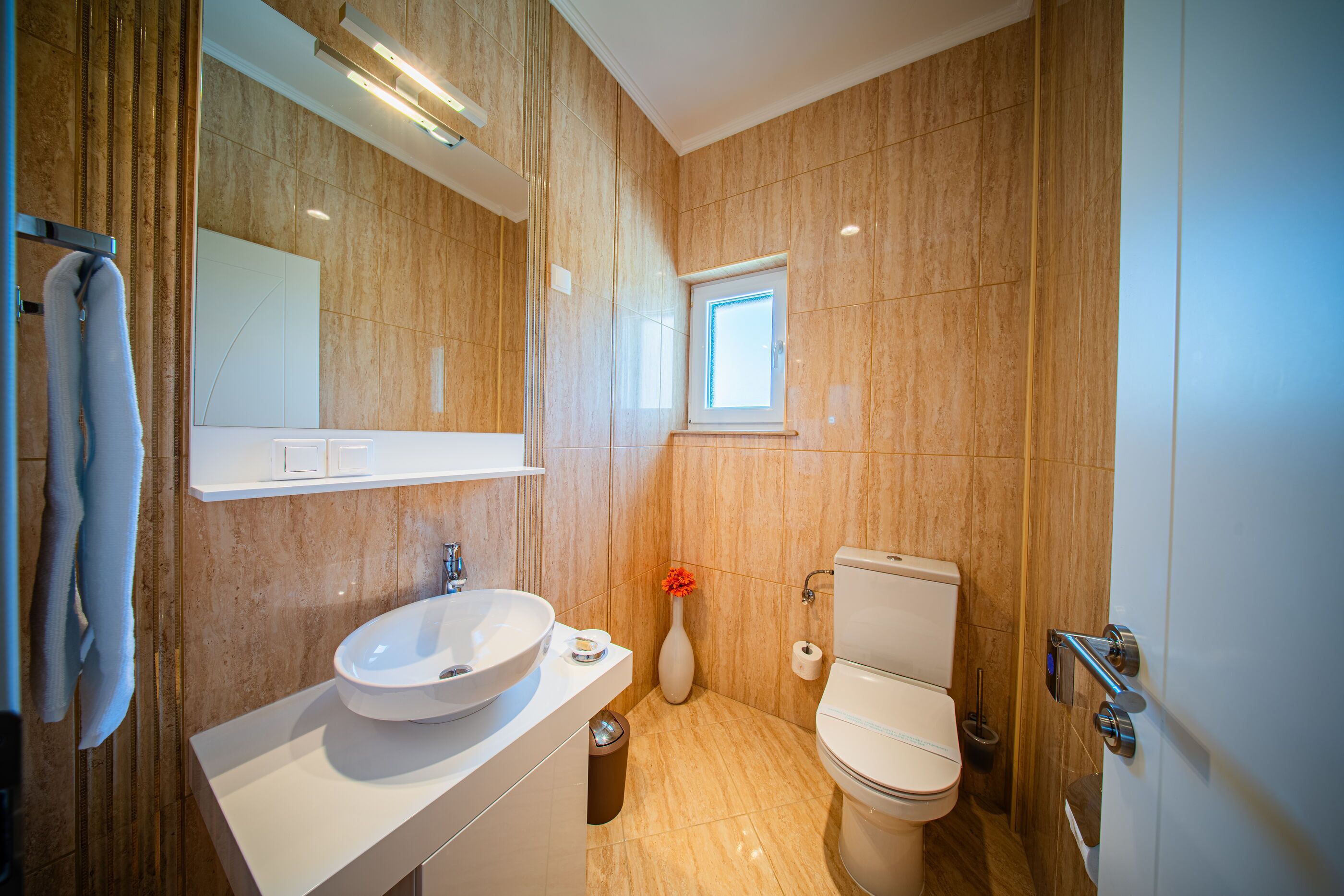 Ein modernes Badezimmer mit einem großen Waschbecken, Toilette und einem Spiegel über dem Waschbecken.