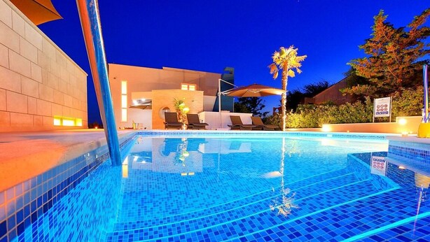 En swimmingpool med kakelbeklädd botten, solstolar och parasoller.