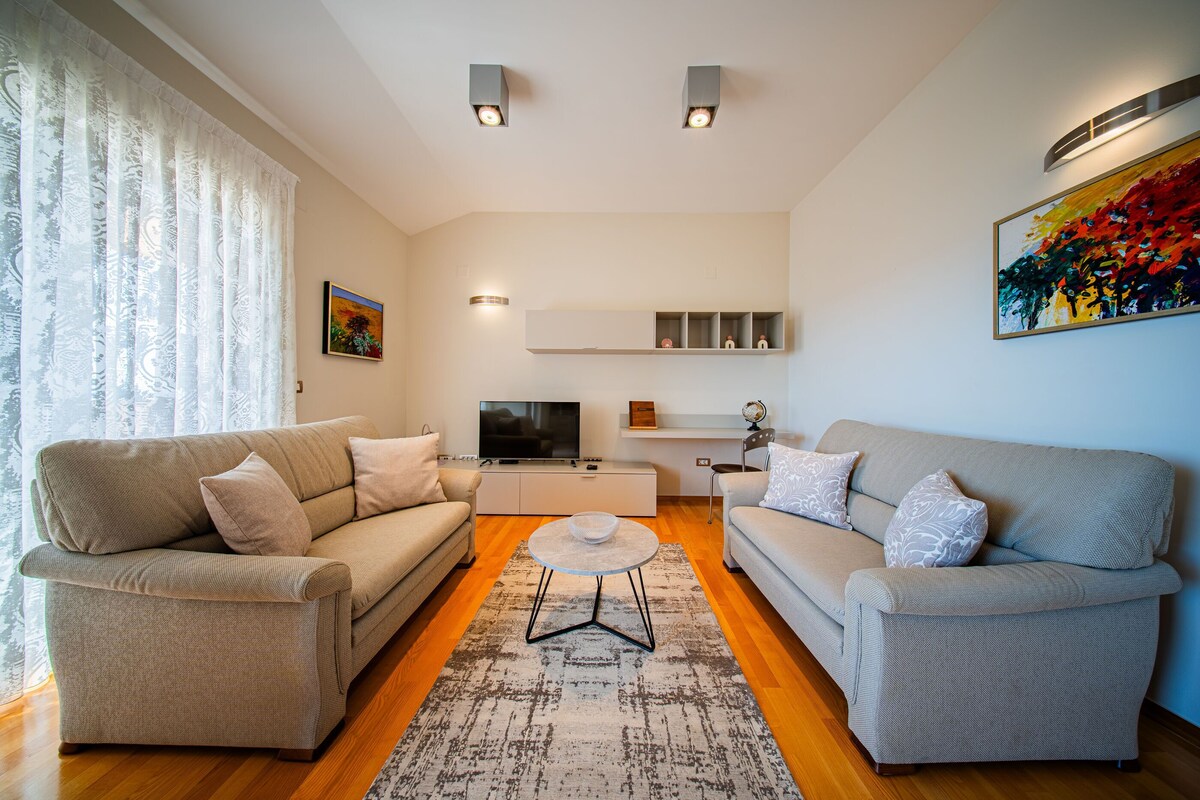 Ein Wohnzimmer mit zwei Sofas, einem Couchtisch, einem Fernseher und einem Gemälde an der Wand.