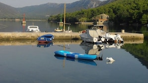 Um lago tranquilo com barcos atracados em um cais, rodeado por montanhas e vegetação.