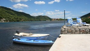 Um barco atracado em cais, com espreguiçadeiras e um muro de pedra.