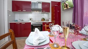 Cozinha moderna com armários vermelhos e área de jantar posta para refeição.