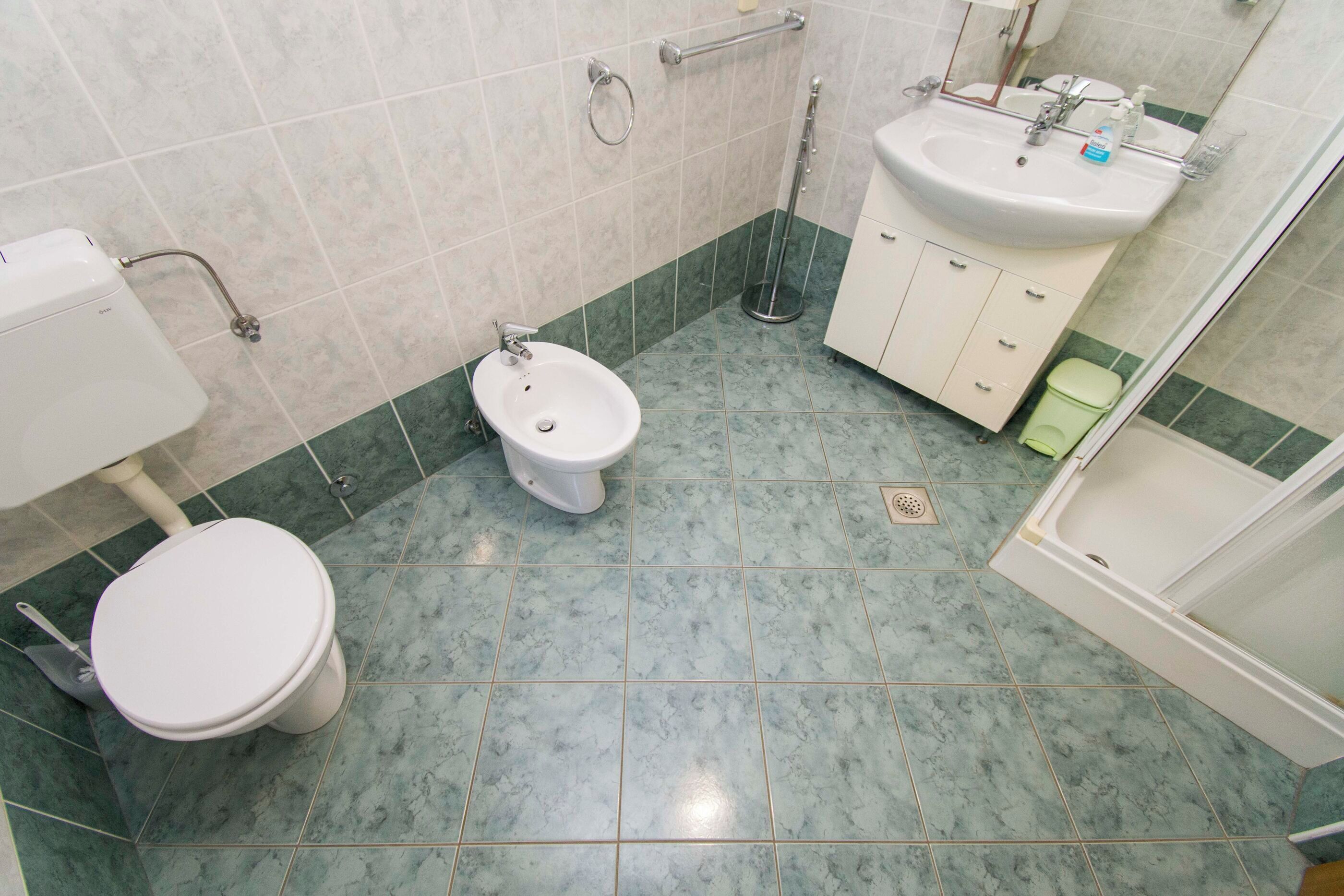 Un baño con inodoro, bidé, lavamanos y ducha.