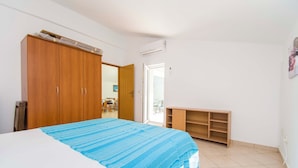 A bedroom with a bed, wooden wardrobe, and a small desk. - Apartment Gordana (Pag)