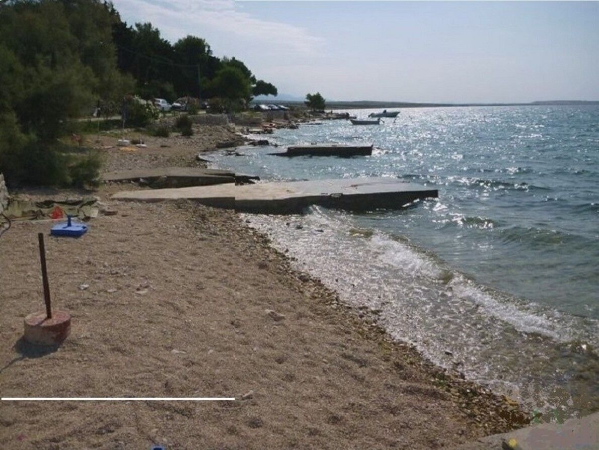 A beach with a sandy shore, wooden walkways, and boats in the water.