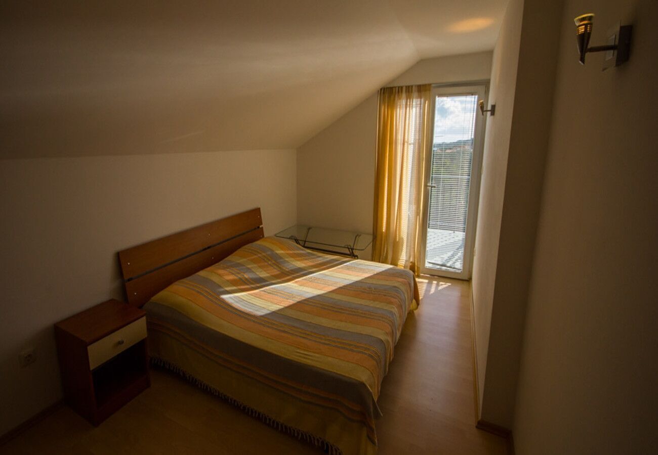 A bedroom with a single bed, a nightstand, and a window with curtains.