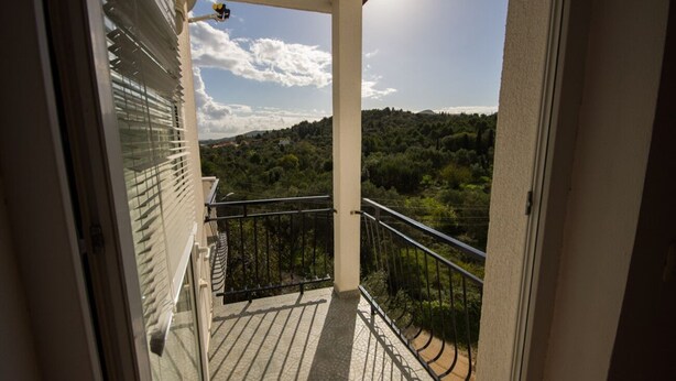 A balcony with a view of a forested hillside. - Apartments Daju (Pasman)