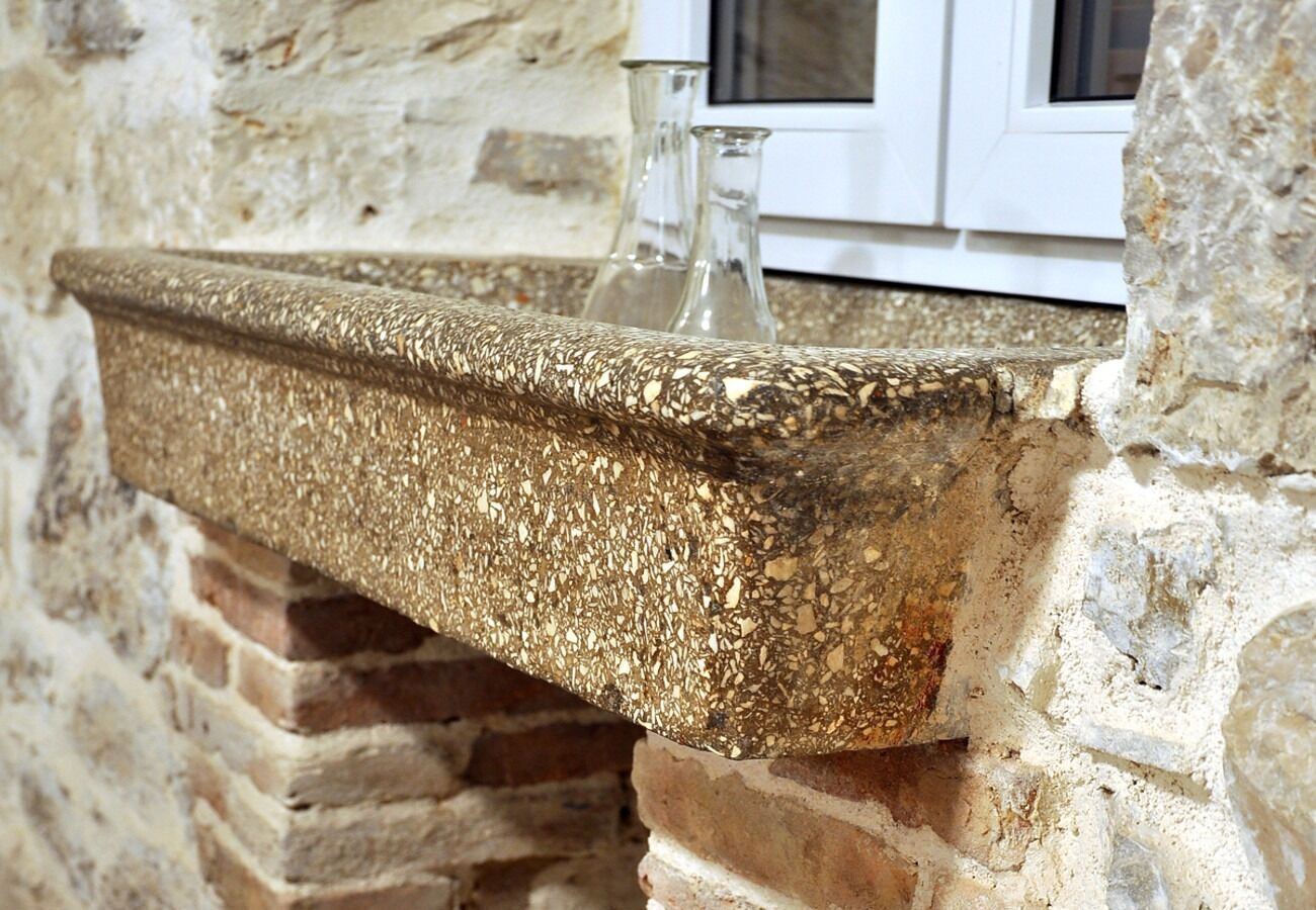 A stone shelf with a textured surface, positioned against a stone wall with a window above.