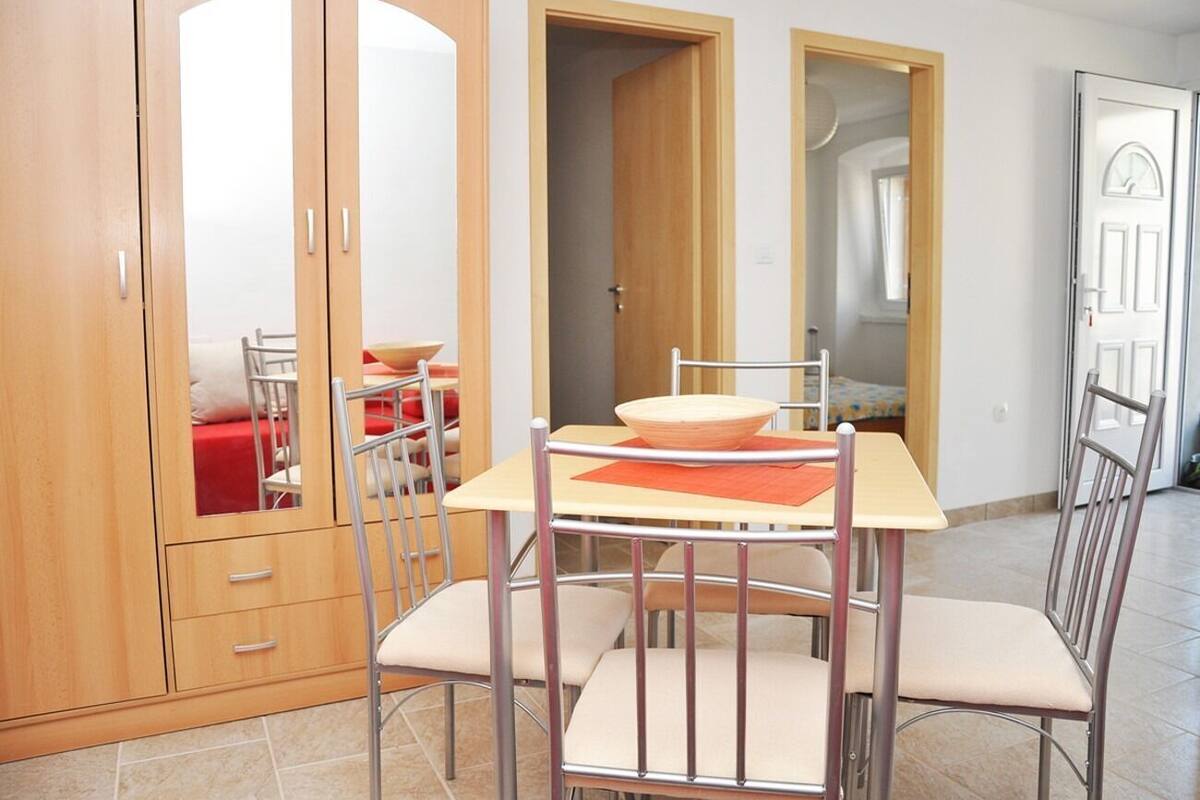 Un coin repas avec une table et des chaises, une armoire en bois et une porte donnant sur une autre pièce.