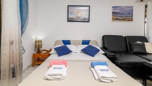 Une chambre d’hôtel avec un lit, une table de chevet, un bureau, un canapé en cuir noir et deux tableaux au mur.