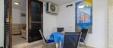 A small dining area with a table and chairs, an air conditioning unit, and a view of a building through a window.