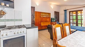 Une cuisine équipée d’un fourneau, de placards et d’un coin repas avec des chaises et une table.