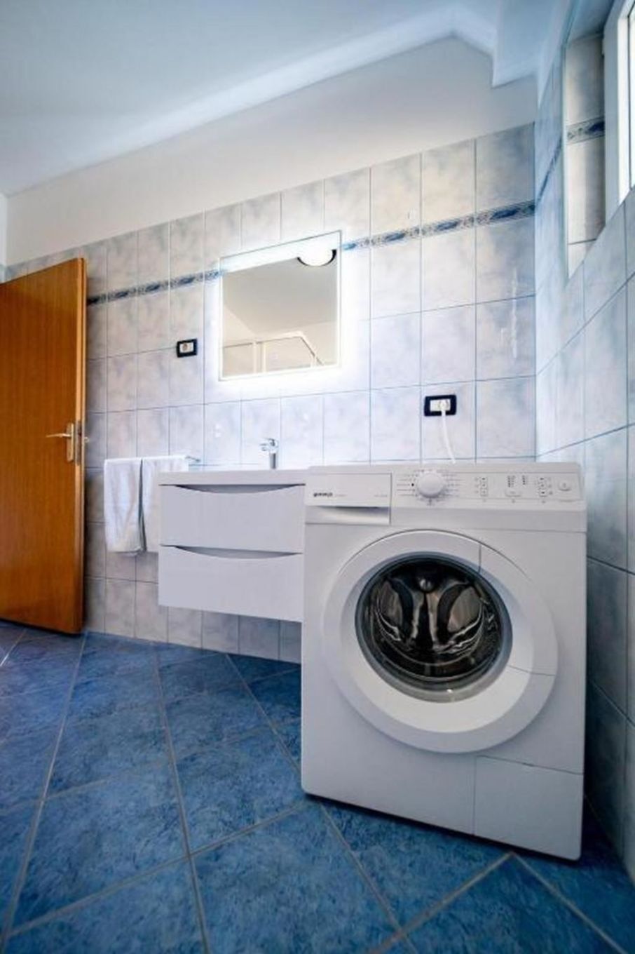 A modern bathroom with a built-in washing machine, a vanity with a mirror, and a towel rack.