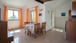 A dining area with a table set for four, wooden chairs, and a vase with flowers. - Apartments Ana (Solta)