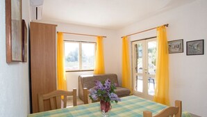 A dining area with a checkered tablecloth, wooden chairs, a vase with flowers, and a sofa. - Apartments Ana (Solta)
