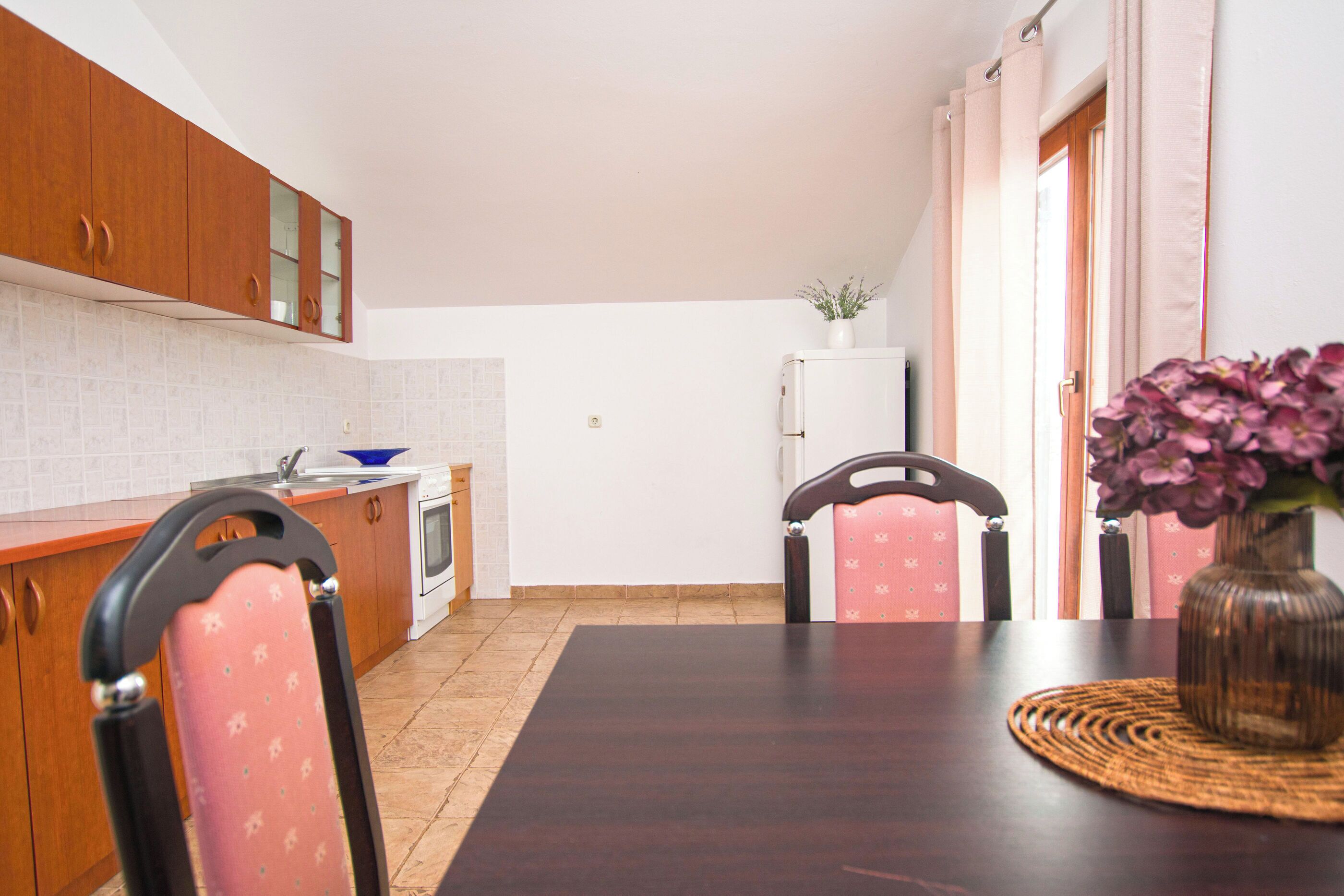 Une cuisine de taille réduite, dotée de meubles en bois, d’un réfrigérateur blanc et d’une table à manger avec des chaises.
