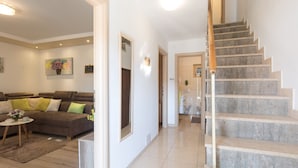 Un salon spacieux comprenant un canapé, une table basse et un escalier menant à une autre pièce.