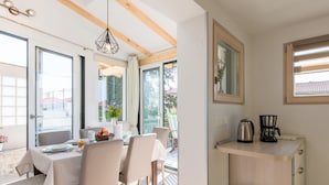 Une cuisine moderne avec un coin repas, dotée d’un plafond en bois, de grandes fenêtres et d’un petit évier.