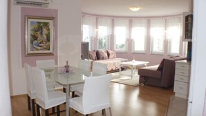 A spacious living area with a dining table, white chairs, a sofa, and a coffee table. - Apartments Marin (Biograd na Moru)